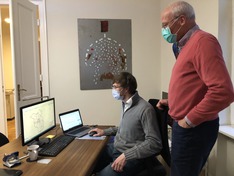 Das Foto zeigt Dr. Klaus Hildebrandt und einen Mitarbeiter vor zwei Monitoren an einem Schreibtisch.